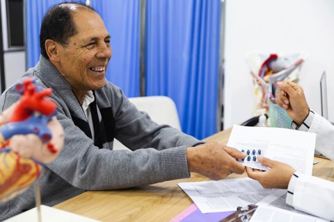 An elderly male patient receives attentive care from a young female doctor in a Latin American