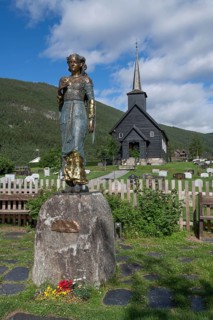 Wooden church in Sel with a cemetery and a statue of Kristian Lavranstochter, the main character