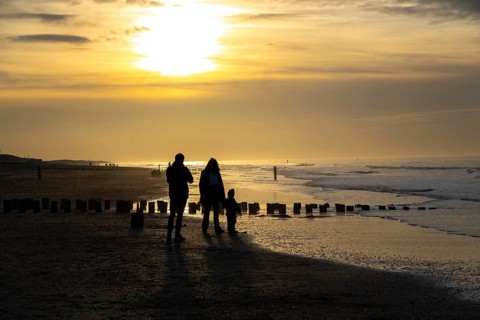 Winter on the North Sea, sunset at sea, beach walkers, coastal protection, through wooden posts,