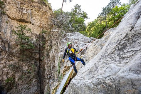 Adventurer rappelling down a steep rock face during a canyoneering trip in Matacanes, Nuevo Leon,