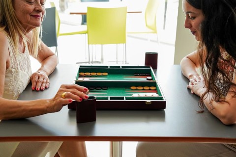 Mother and daughter enjoy a leisurely backgammon game at a modern cafe The board, with its classic