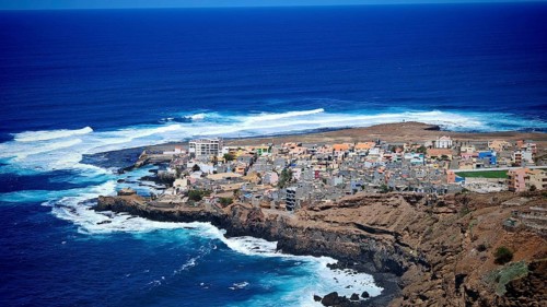 View from above of a small coastal village with blue waves hitting the cliffs, hiking, Ponta do