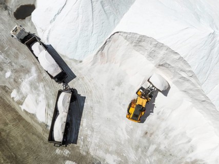 Lorry and excavator at the salt heaps of the Walvis Bay Salt works. Aerial view. Drone shot. Walvis