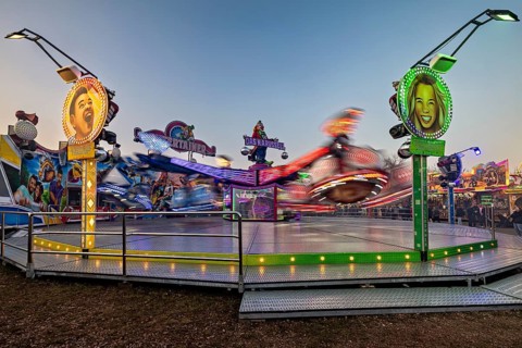 A spinning ride with colorful lights and blurred movements at dusk, carousel and the hustle and