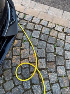 A yellow charging cable of an electric car lies on paving stones, Düsseldorf, Germany