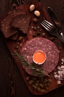 Beef tartare, with egg, capers, gherkins and bread, toned, top view, close up, horizontal, no