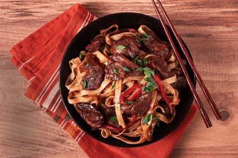 Udon noodles with beef in Mongolian style, with green onions and vegetables, served in a black