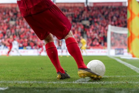 Footballer takes the corner. Detail of player's legs and the ball during soccer match in Lodz,