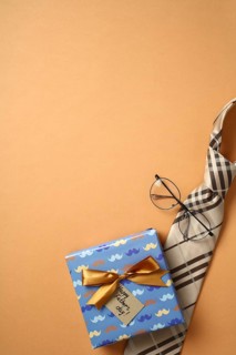 Top view of a colorful gift box with a golden bow and Happy Father's Day tag, accompanied by a