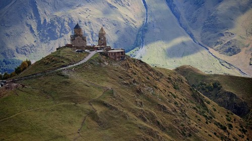 Historic Gergeti church on a hill surrounded by majestic mountains, Stepantsminda, Caucasus,