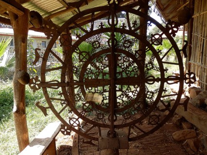 A decorative metal wheel with intricate patterns in front of an orthodox monastery in Ethiopia