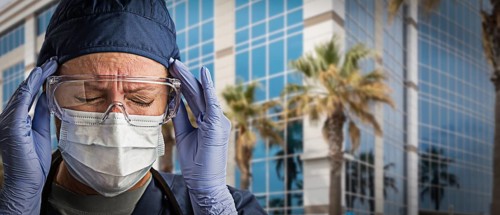 Grimacing Female Doctor or Nurse Wearing Scrubs, Protective Face Mask and Goggles