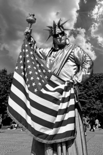 Man with US flag disguised as a statue of Liberty in Central Park, New York City, USA