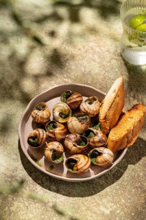 A gourmet plate of baked escargot generously topped with melted butter and fresh parsley,