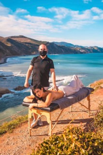 A young man performing a nature massage on the coast near the sea, a dream come true, masseur with