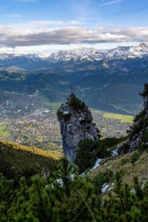 Rocky peak with summit cross, view of Garmisch-Partenkirchen and mountain panorama, hike to