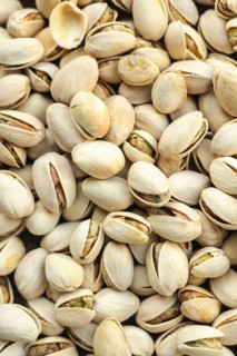A detailed close up of pistachios in their shells, showcasing the texture and subtle colors.