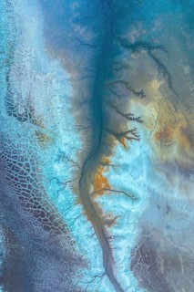 A stunning aerial view captures a mesmerizing landscape resembling icy patterns, blending vibrant