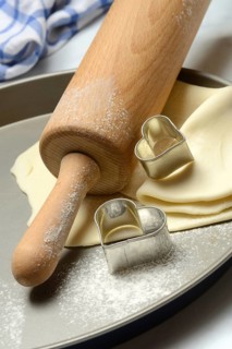 Rolled dough on cake tray with dough rollers and cookie cutters
