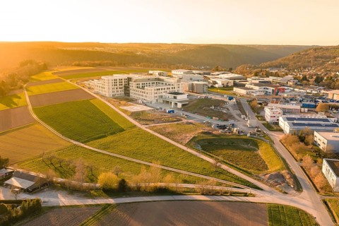 Wide aerial view of a landscape scene with buildings and green fields in the evening light, new