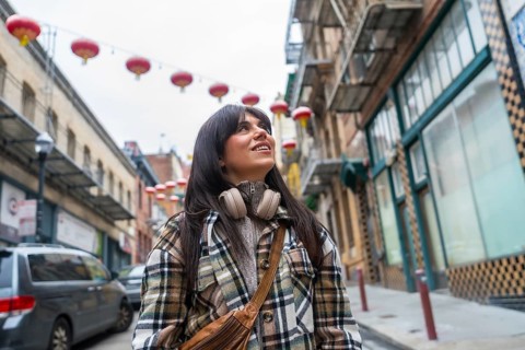 Young woman smiling and looking up, experiencing the vibrant culture and traditional red lanterns