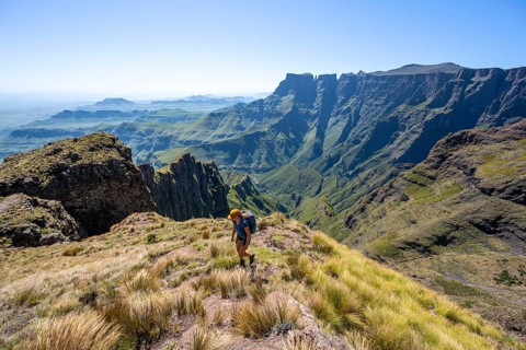 Young hiker looking at the impressive mountains and cliffs of the Drakensberg Mountains, hiking