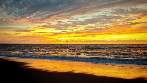 Beach at sunset with vivid colors in the sky and calm waves in the sea, Tarrafal de Monte Trigo,