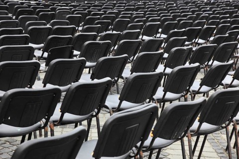 Chairs covered with gray plastic stand in rows in a function room, empty, vacant, seating