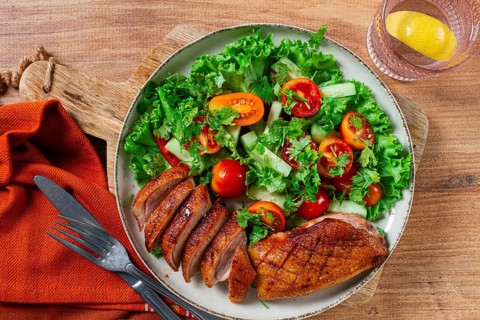 Delicious grilled duck breast served with fresh garden salad and cherry tomatoes at a rustic dining