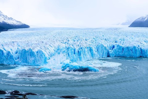 Perito Moreno glacier, calving front with blue glacial ice and turbulent water following an ice