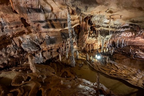 Stalactites and stalagmites, rock formations in a stalactite cave with water basin, Grotta del