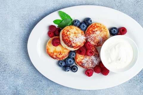Breakfast, cottage cheese cakes, with fresh berries, and sour cream, top view, close-up, no people