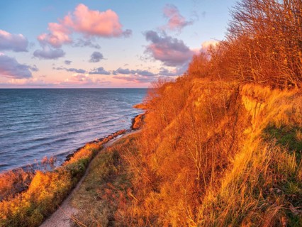 Natural coastal landscape on the Baltic Sea in the last evening light, glowing pink clouds, view of