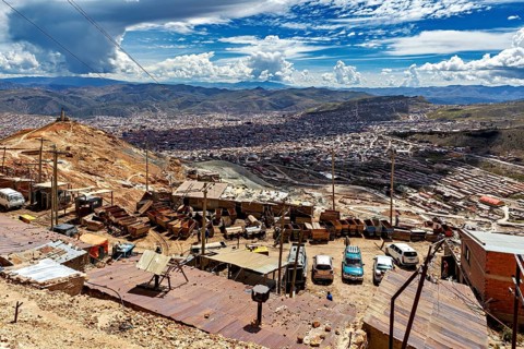 View from above of an urban landscape with vehicles, carts and hills under a dramatic sky, The