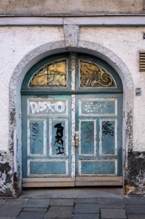 Weathered arched door covered with gafitti on a historic town house in the old town of Augsburg,