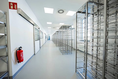 Long corridor with metal shelves and a fire extinguisher in a sterile environment, operating room