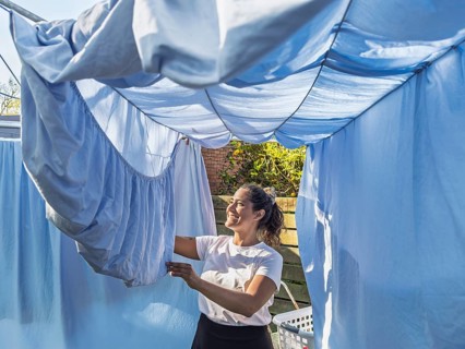 A cheerful woman attends to daily chores in an Australian backyard, hanging fresh laundry on a