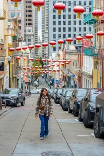 Young woman confidently walking along a street in san francisco's chinatown, surrounded by
