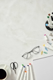 Top view of a neatly arranged artist's workspace featuring a sketchbook surrounded by colorful