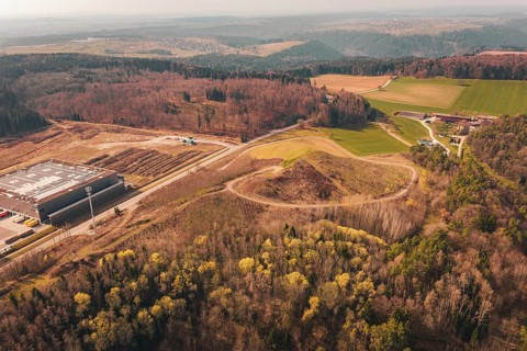 Extensive panoramic view of a hilly area with buildings, roads and surrounding forest, old deposit