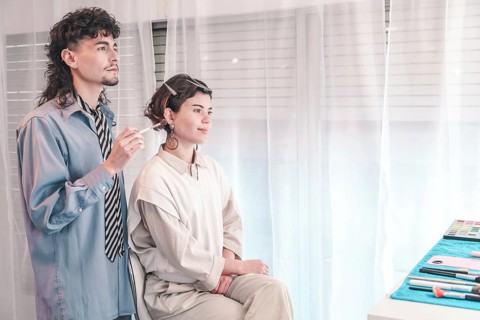 Professional makeup artist applying makeup on a model's face in a bright, airy beauty salon,