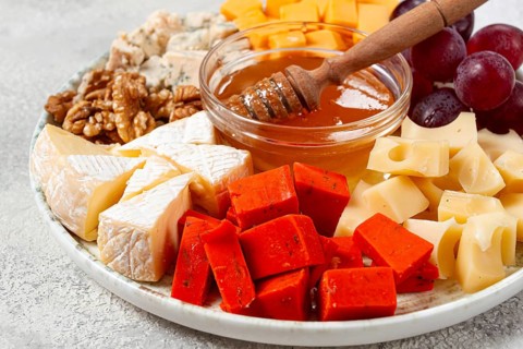 Appetizer, assorted cheese, with nuts and honey, on a round plate, top view, no people