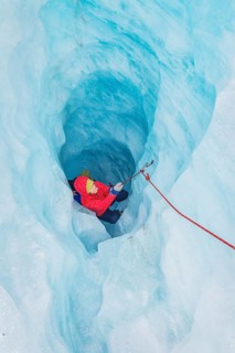 Mountaineer moving up ice cave, Fox Glacier, Westland National Park, South Island, New Zealand