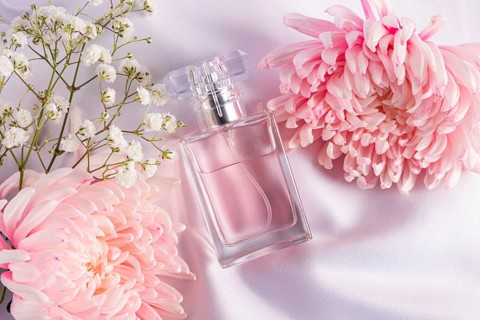 An elegant scene featuring a pink perfume bottle surrounded by delicate pink and white flowers on a