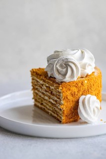 Slice of homemade honey cake, rich with layers of flavor, topped with a creamy sour cream sauce and