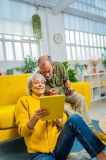 Vertical photo with copy space of a caucasian senior couple commenting and sharing digital tablet