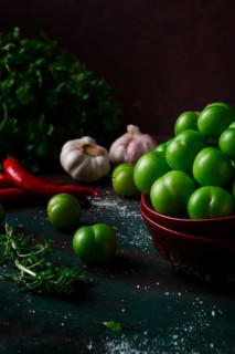 Tkemali, green cherry plum, with ingredients for sauce, cilantro, mint, hot pepper, garlic, on a