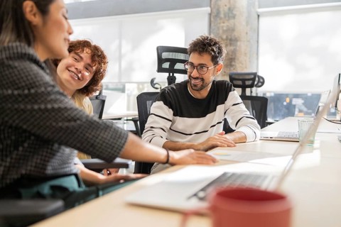 A group of coworkers engaged in a collaborative discussion at a modern office Smiling and