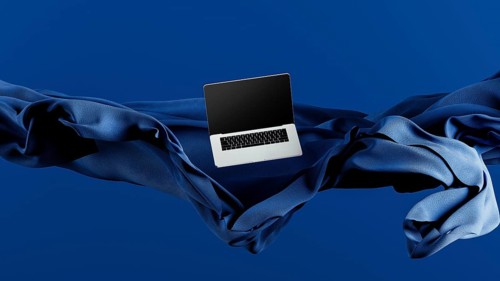 A sleek laptop is placed atop smooth fabric, showcasing its lightweight design against a rich blue
