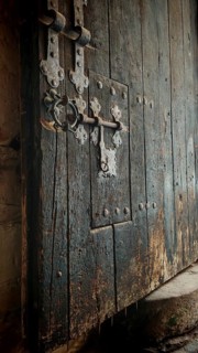 Old, massive wooden door with decorative metal fittings and visible patina, gate to the fortress,